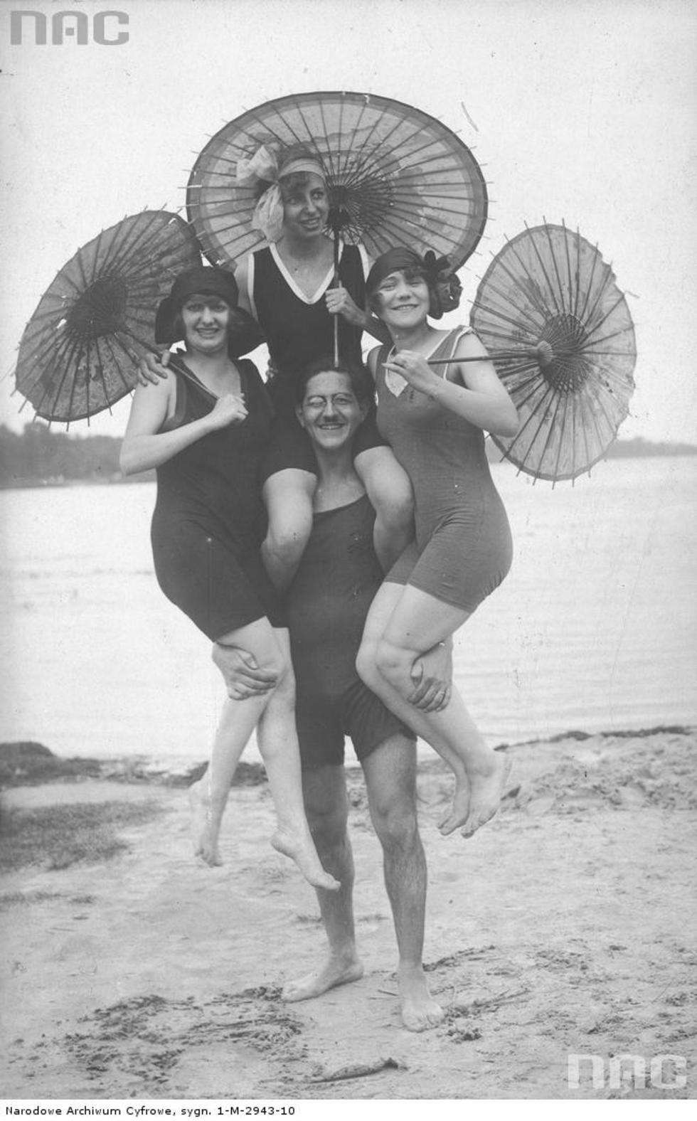  Model z modelkami na rękach pozujący na plaży w strojach kąpielowych. 1918 - 1939 