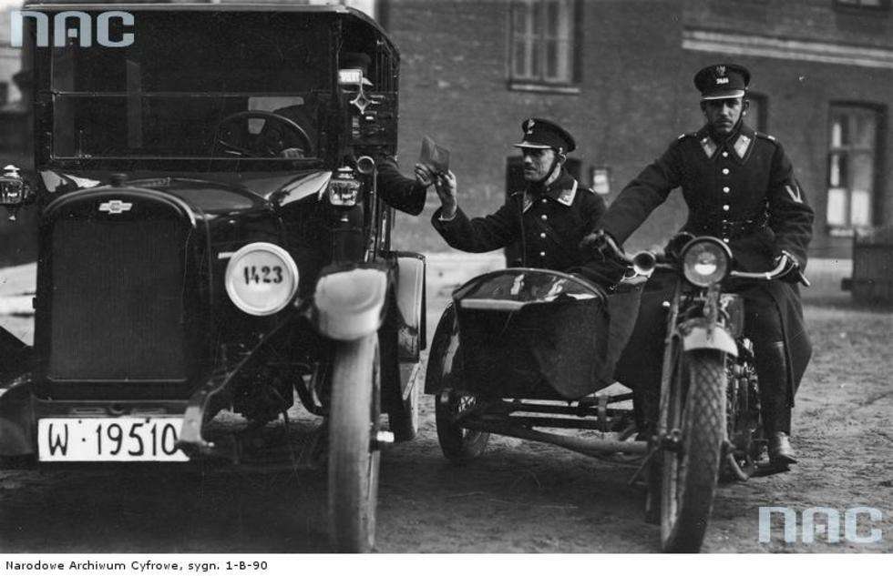  Funkcjonariusze Policji Państwowej podczas pełnienia służby. W trakcie patrolu drogowego na motorze sprawdzają dokumenty kierowcy. 

Data wydarzenia: 1925-1935 
