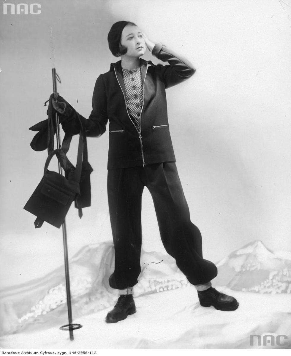  Moda francuska. Modelka w stroju narciarskim, grubych butach, nakryciu głowy i torebką sportową. 1930 r.

