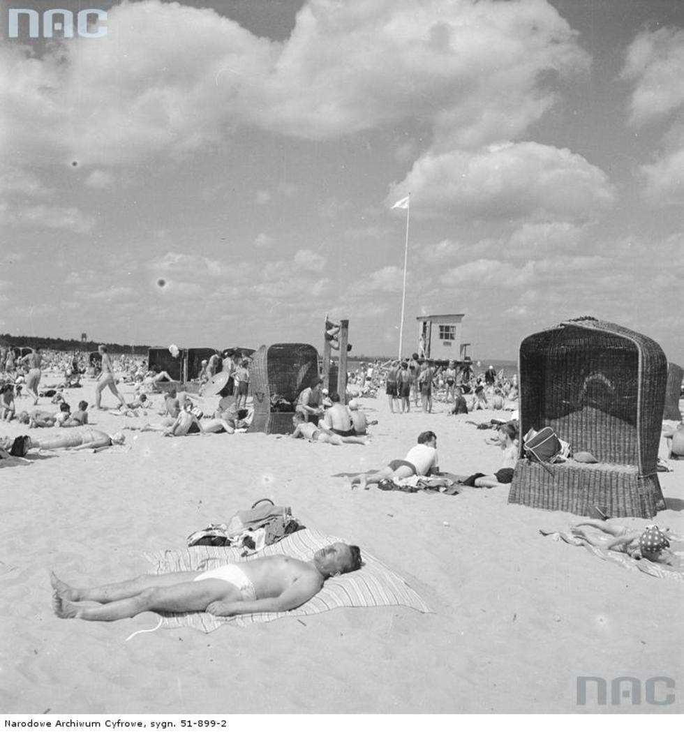  Letnicy w strojach plażowych opalający się nad morzem Bałtyckim. Na piasku stoją kosze plażowe. Na dalszym planie - nad brzegiem morza - widać budkę ratownika.
Data wydarzenia: 1958 
Fot. <a href="http://www.audiovis.nac.gov.pl/obraz/168780/9f1e8792fba140cb3210eb4d1f012369/">NAC</a>