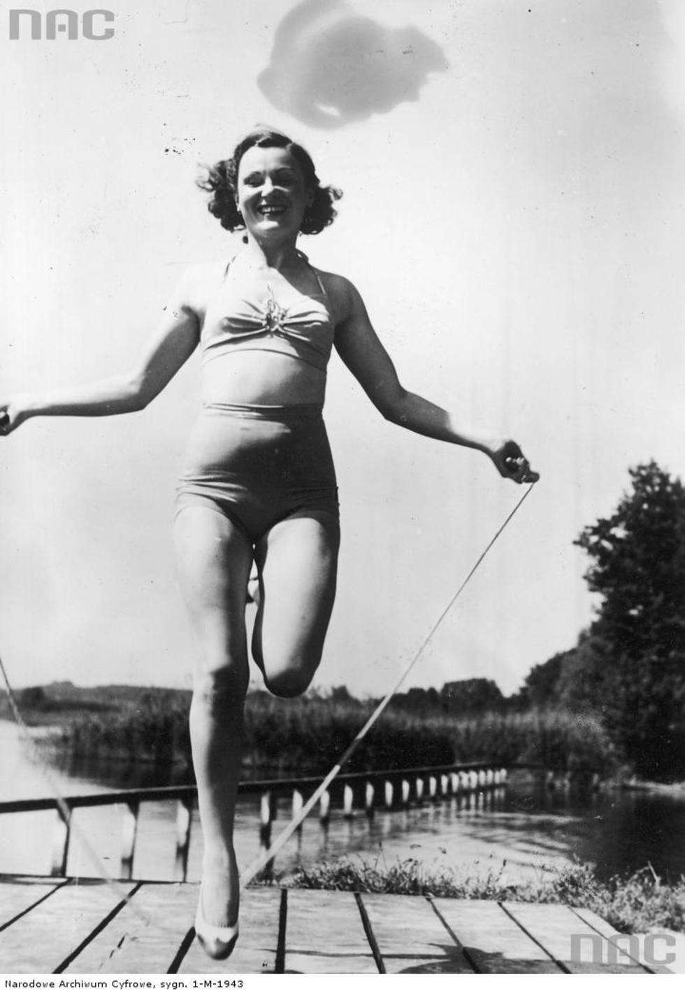  Aktorka Maria Andergast w kostiumie kąpielowym skacząca na skakance podczas wakacji nad jeziorem w nieznanym miejscu. 1939 r. Fot. <a href="http://www.audiovis.nac.gov.pl/obraz/184192/0a5a08ea8d783eb66d48481d17752e5d/">NAC</a>