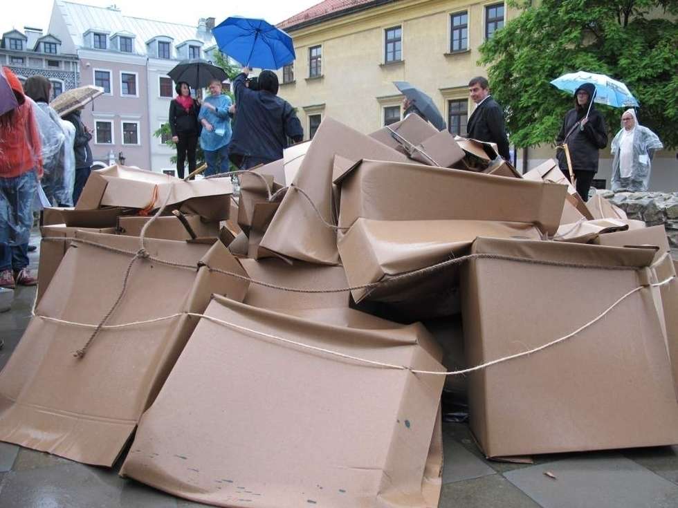  Deszcz działał na korzyść &#8222;Podarków z nieba&#8221; które zrzucił na plac Po Farze Andrij Sahajdakowski. Strugi wody wymywały z pudeł błękitną farbę. Pracę ogląda (bez parasola) Mirosław Haponiuk, dyrektor Ośrodka Międzykulturowych Inicjatyw Twórczych &#8222;Rozdroża&#8221;, który organizuje Open City