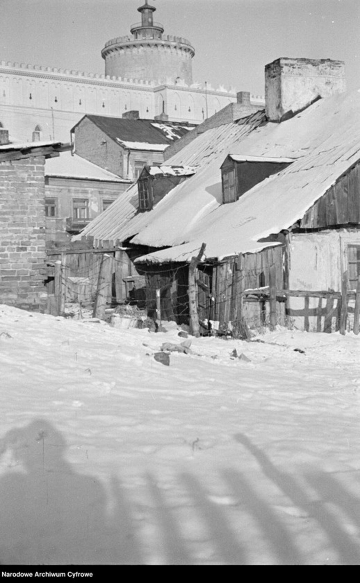 <p>Drewniane domy przy ul. Krawieckiej - z prawej dom pod nr 7. W tle fragment Zamku Lubelskiego i wieża (donżon). Zdjęcie z 1935 r.</p>