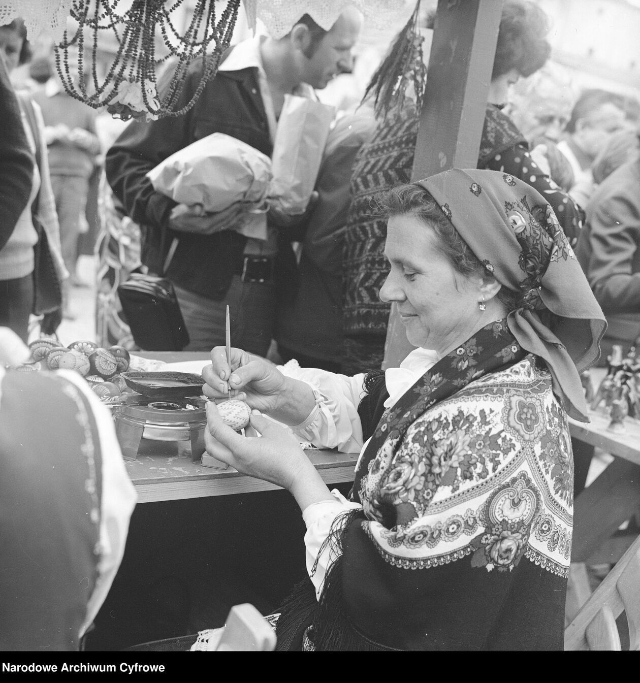  <p>Kobieta w stroju ludowym maluje pisanki w straganie na rynku w Kazimierzu Dolnym</p>