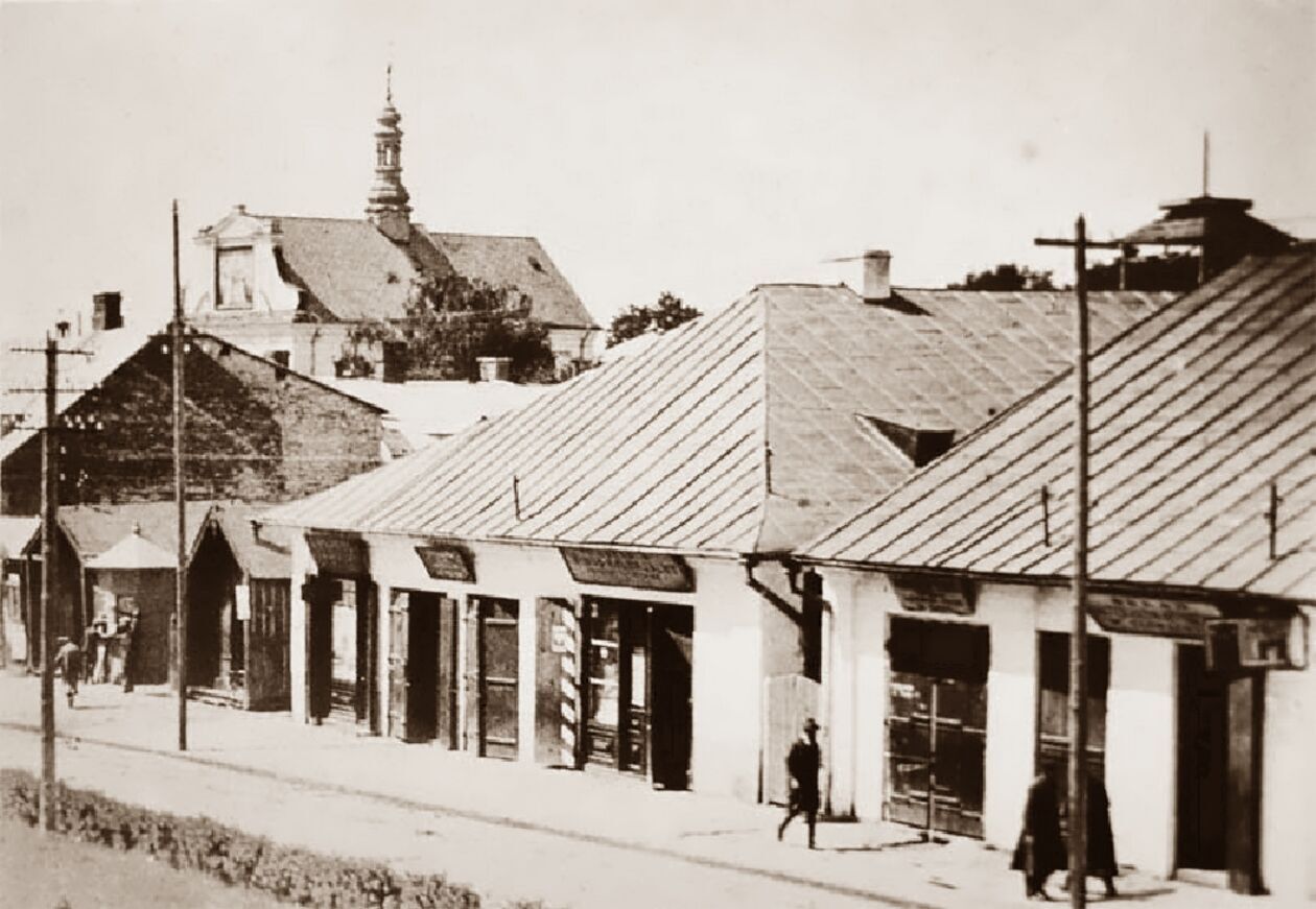  <p>Lata 1925-1930. Plac Wolności pierzeja zachodnia, z kt&oacute;rej nie został już żaden budynek. Po lewej za słupem ogłoszeniowym trzy drewniane budki stoją na miejscu dawnego ratusza.</p>