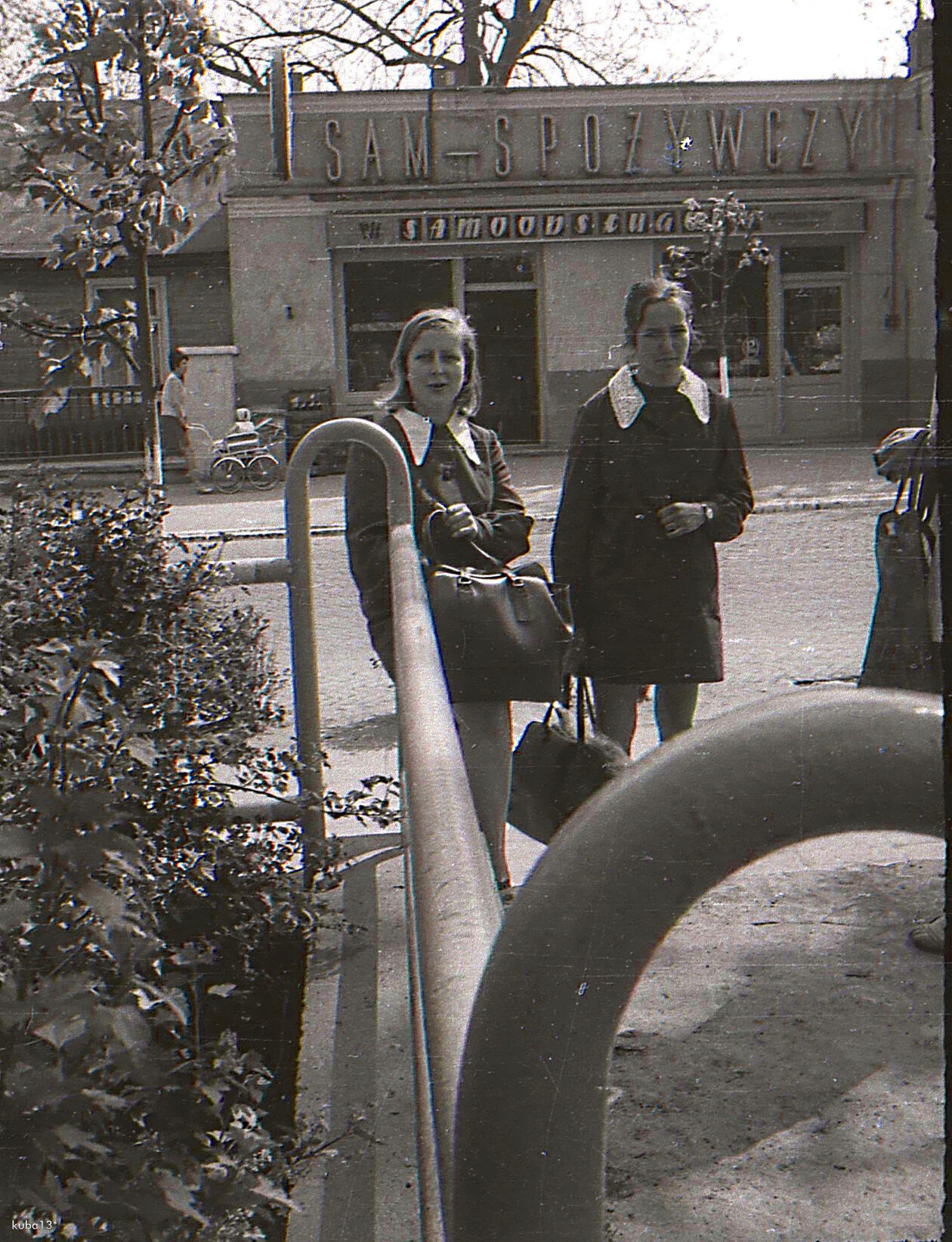  <p>Lata 1970-1972. Widok na słynną Bombonierkę (do tej pory ta nazwa widnieje na sklepie) czyli sklep przy obecnej ul. 3 Maja. Dziewczyny stoją przy ogrodzeniu parkowym przy ul. Majora Dobrzańskiego. I po lewej drewniana ciekawostka - nieistniejący dom.</p>
