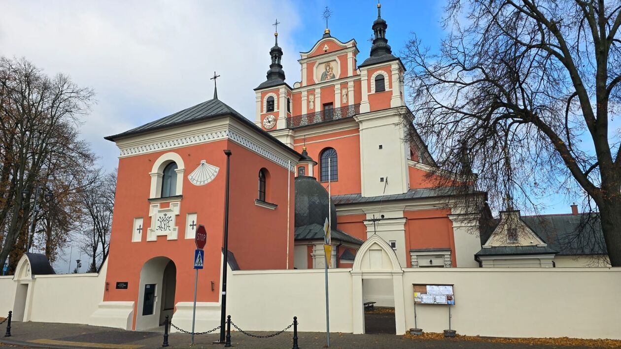 <p>rama dzwonnica i ogrodzenie, po zakończeniu prac konserwatorskich . W tle elewacja frontowa kościola. Zdjęcie z archiwum WUOZ w Lublinie.</p>