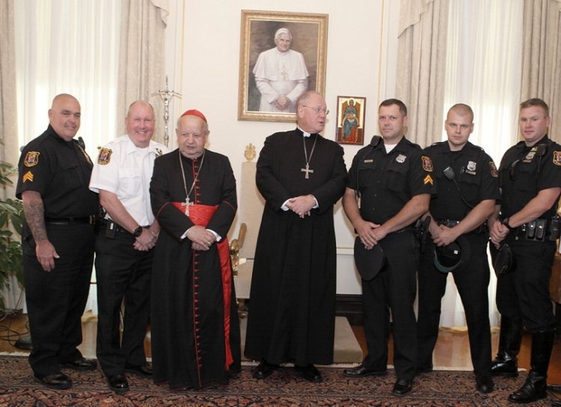 Kardynał Timothy Dolan (w środku) i jego krakowski gość. Obok asysta policyjna polskiego hierarchy. 