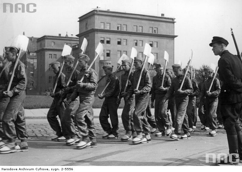 Uroczystość 4-lecia Służby Budowlanej Baudienst. Kolumna robotników z łopatami na ramionach w marszu