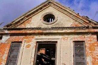 Przez bramę zrujnowanego zabytku wiedzie czynna droga powiatowa