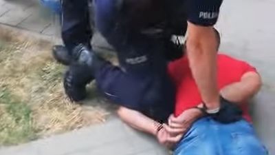 Kadr z filmu z interwencji policjantów. Jeden z funkcjonariuszy przytrzymuje poszukiwanego do odbycia kary pozbawienia wolności 22-latka, skazanego za kradzieże