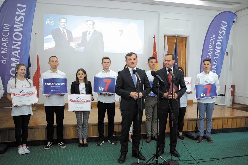 Podczas konferencji za ministrami stali młodzi ludzie ubrani w koszulki z logo PiS i nazwiskiem Romanowskiego, trzymający plansze z cyfrą 7