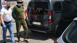 Jeden z aresztowanych mężczyzn prowadzony przez  policjantów.