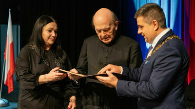 Ksiądz Czyżewski odbiera wyróżnienie od przewodniczącej rady miasta, Bożeny Krygier i prezydenta Puław, Pawła Maja