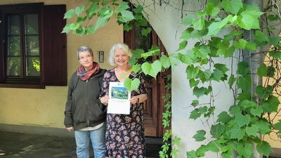 Agnieszka Drwal i Maria Skowrońska-Drwalowa z dyplomem Skarbu Kultury Przestrzeni przy winorośli pod arkadą budynku na Wyszyńskiego 4