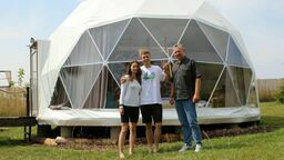 Sara Jakubiak, Michał Wójcik i Krzysztof Wójcik na tle jednego ze swoich glampingowych namiotów