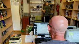 Pracownicy kompleksu kulturalno-oświatowego w trakcie wypełniania obowiązków. Na zdjęciu jeden z pracowników biblioteki podczas wprowadzania książek do systemu oraz skazany w trakcie układania oddanych książek. 