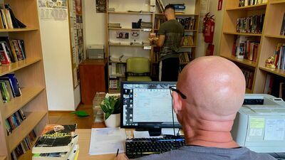 Pracownicy kompleksu kulturalno-oświatowego w trakcie wypełniania obowiązków. Na zdjęciu jeden z pracowników biblioteki podczas wprowadzania książek do systemu oraz skazany w trakcie układania oddanych książek. 